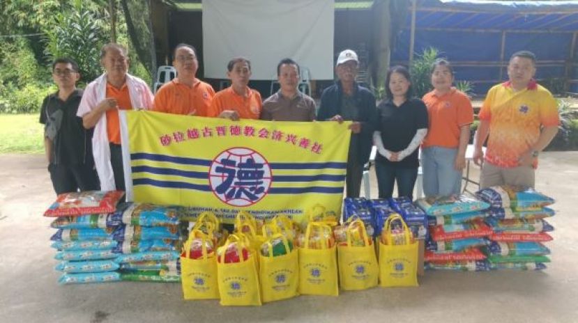 济兴善社总务林庆鸿（左2起）、福利陈威溱移交布施食品予甘榜杜拉村长仲生与众人合影。右起为副福利佘信志、方慧颖，左2是陈中兴医师。