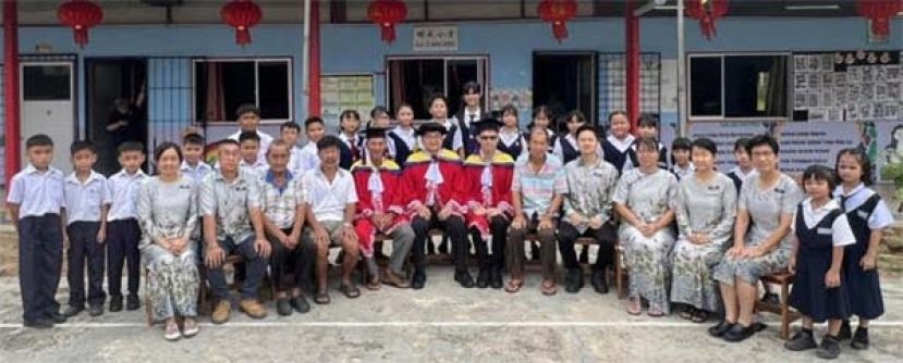 拿督吴标生（坐左六）与明成小学董事、全体师生合影与明成学校校园内。坐左五为该校董事长吴田森、坐左七为校长吴奕利。