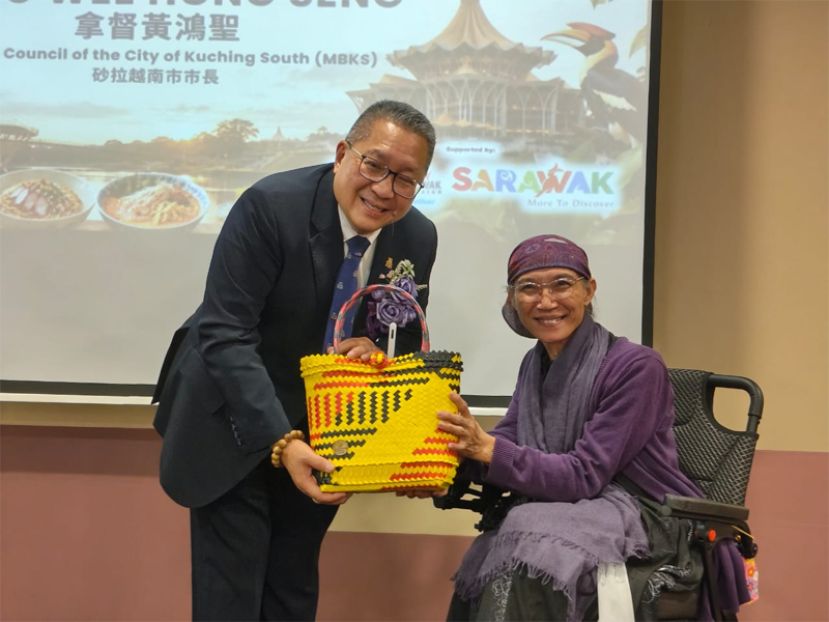 古晋喜乐双福关怀协会创办人沈秋香（右）赠送纪念品予古晋男市市长拿督黄鸿圣（左）。