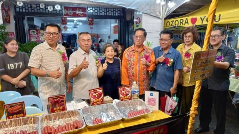  天猛公拿督陈如飞（右4）参观美食摊位与庆典大会会长甲必丹林传政伉俪（右5起）、拿督蔡传伟等人合影。右起为庆典顾问薛华东、甲必丹陈楚燕、砂晋汉省广东会馆会长沈象文。