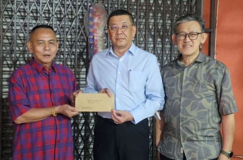 甲必丹林传政（左）移交主宾邀请函予拿督斯里黄良杰，右为薛华东。