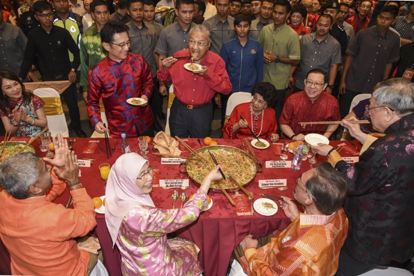 图示：马哈迪（后排左3）在捞生环节结束后，大口品尝鱼生。后排左起为关美圆、戴良业、西蒂哈斯玛和林冠英；前排左起为格巴拉克里斯南、旺阿兹莎、安华和钟廷森。