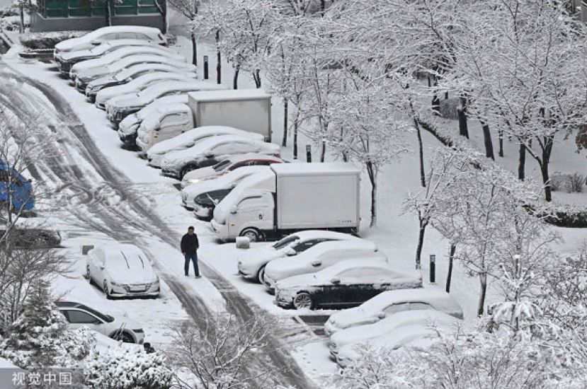 韩国京畿道高阳市22日降雪，民众在停车场铲除积雪。