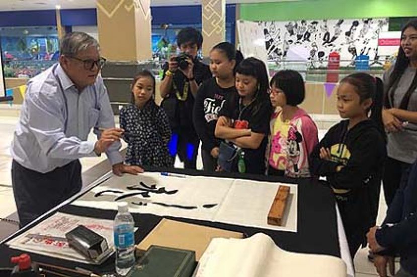 图示：杨添木正教导学生们写书法的技巧。