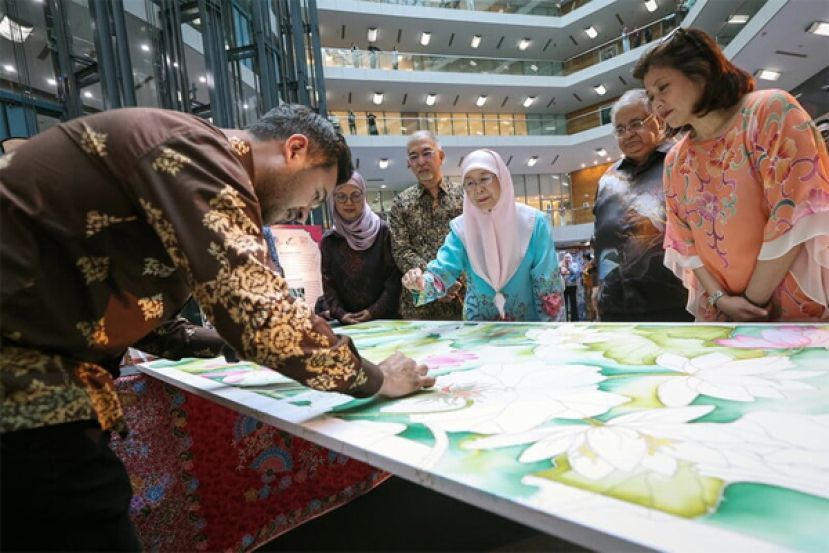 旺阿兹莎（中）欣赏本地峇迪艺术人绘画相关作品。