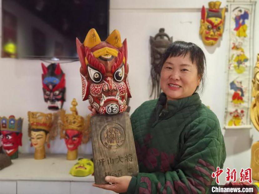 杨云霞展示自己雕刻的傩面具。