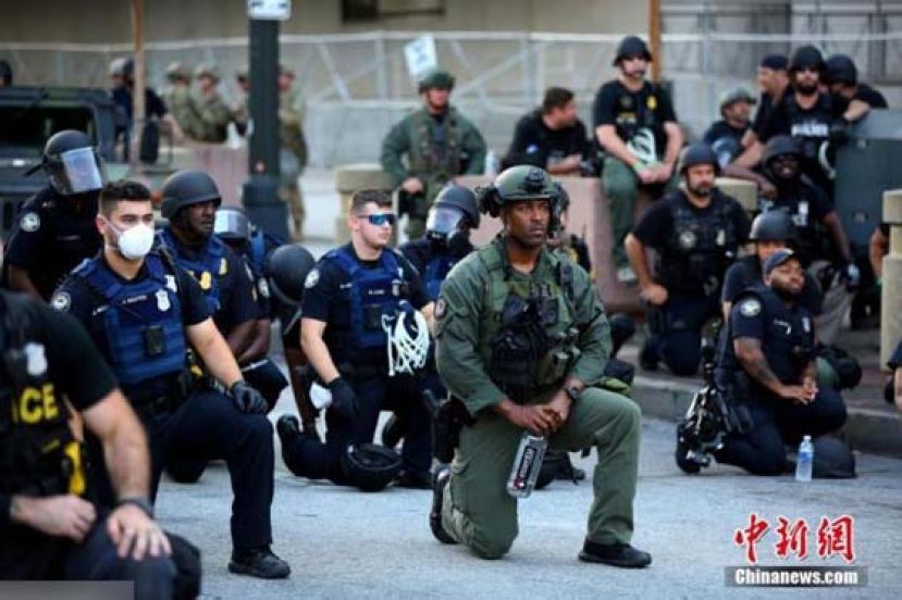 当地时间6月1日，美国乔治亚州亚特兰大市中心，警察和参加游行示威活动的民众一起跪地抗议针对美国非裔男子暴力执法的行为。