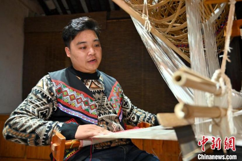 广西来宾市忻城县，&ldquo;90后&rdquo;壮族男子兰培文正坐在传统竹笼机前织锦。