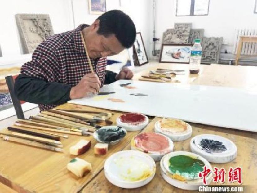 图示：近日，甘肃瓷板画艺人王清路在工作室里进行创作。