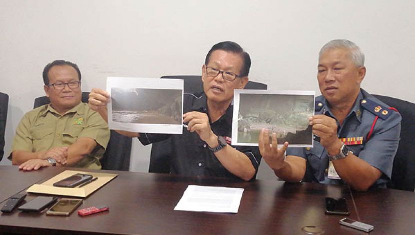 李景胜(中)与美里区消拯局长刘保祥展示山洪爆发前后的鹿洞情形。