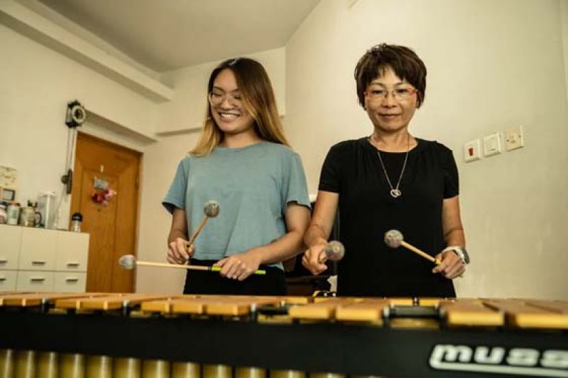 Sharon母女教学相长，教钢琴的妈妈与女儿各手握一棍合奏。