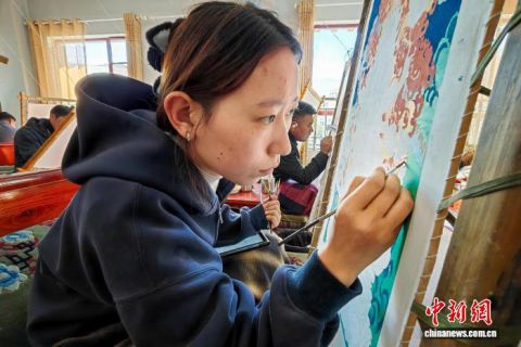 西藏唐卡画院女学员南草吉正为一幅唐卡进行上色。