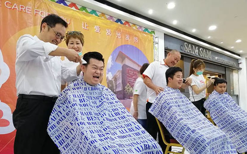 贸消部副部长张健仁（左一）操刀，为古晋区国会议员俞利文剃光头。