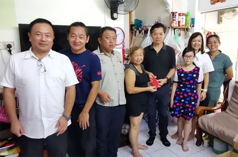 晋汉连省华总会属下福利组一行人，在该会副会长甲必丹陈国璋（左一）丶福利组副主任李国豪（左二）丶华青团团长甲必丹陈德明（左三）丶妇女组主任张慧娇（右二）及妇女组理事陈慧萍（右一）的陪同下亲临蔡府进行探访，并由福利组主任彭国良（右四）代表移交一笔福利援助金给蔡国群的太太。