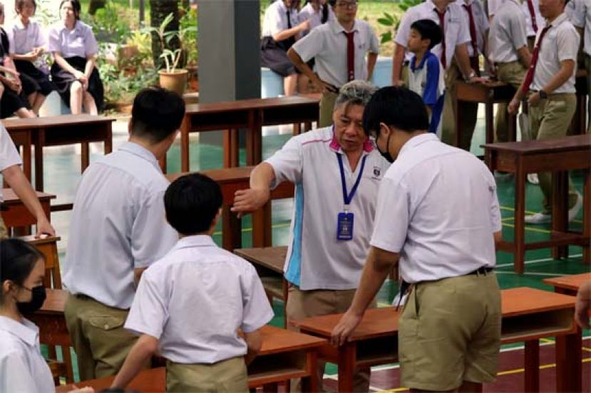 老师带领学生排列义卖会摊位。