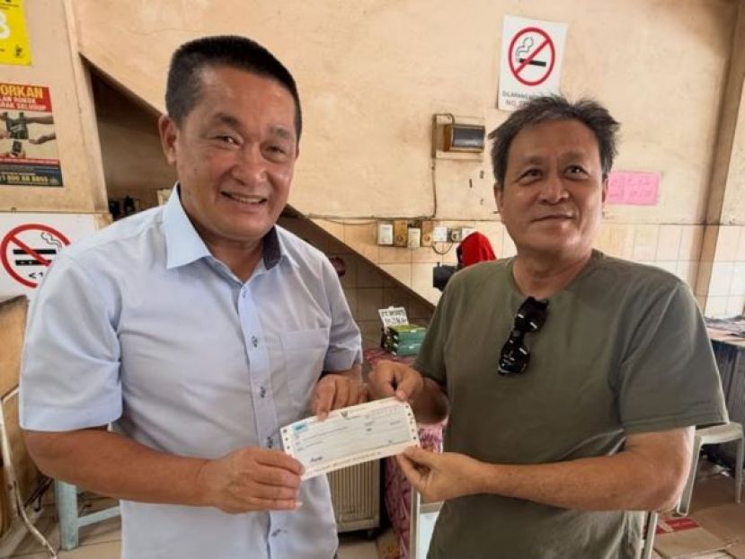 古晋东嶽观主席方文祥太平局绅（右）从施志豪立法议员手中接过拨款。