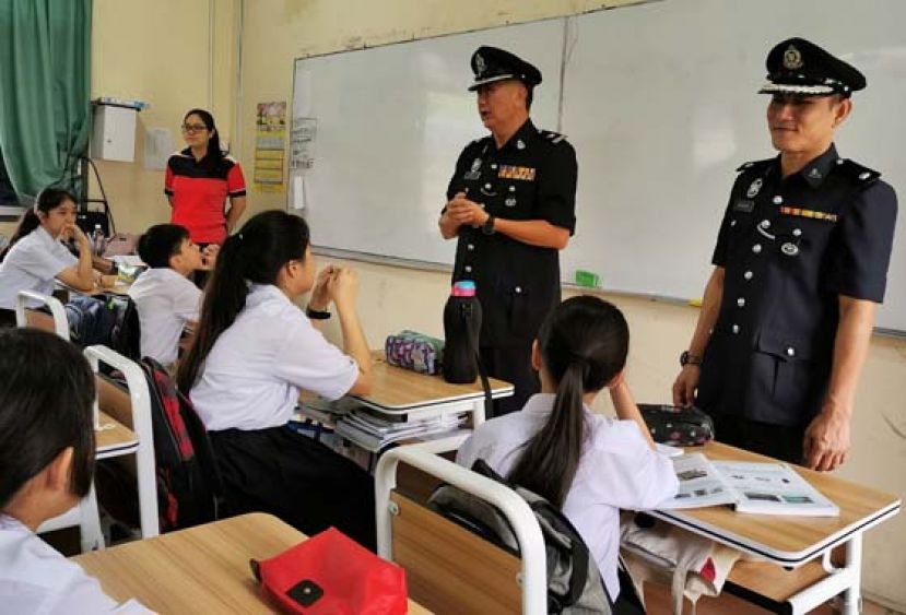 古晋三中学校联系官罗国华（右二）在&ldquo;全国校园活动&rdquo;上，分享网络犯罪作案手法，提醒学生勿轻易受骗。