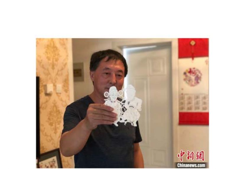 李宝峰在展示剪纸作品。