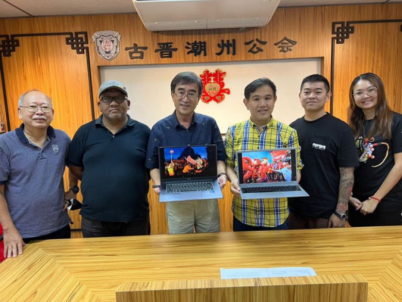 摄影赛评审成绩出炉后，古晋潮州公会青年团团长黄伟忠（右三）和评审之一的砂拉越摄影学会会长田华昌（左三）展示手提电脑荧幕显现的两个组别的第一名摄影作品。右一及二分别是古晋潮州公会青年团副秘书杨匀声和副资讯组长陈保燊。左一是评审之一的砂摄影学会的周胜国及另一评审砂总理署公关单位的莫哈末莱雅斯（左二）。
