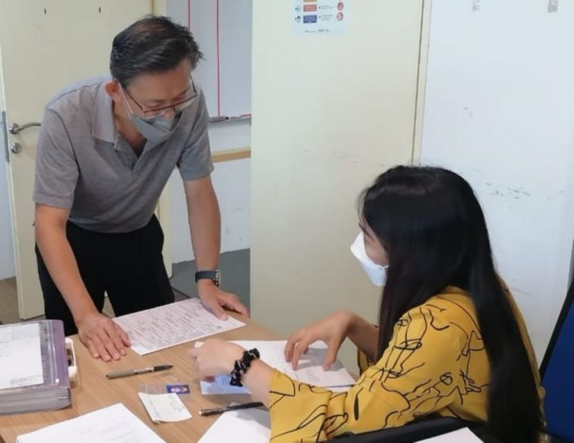 薛华东（左）助本地出生无国籍孩童向当局人员提呈临时证件申请表。