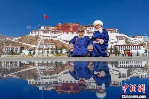 来自内蒙古锡林郭勒盟乌珠穆沁草原的游客宝音(左)和爱人在布达拉宫广场合影。