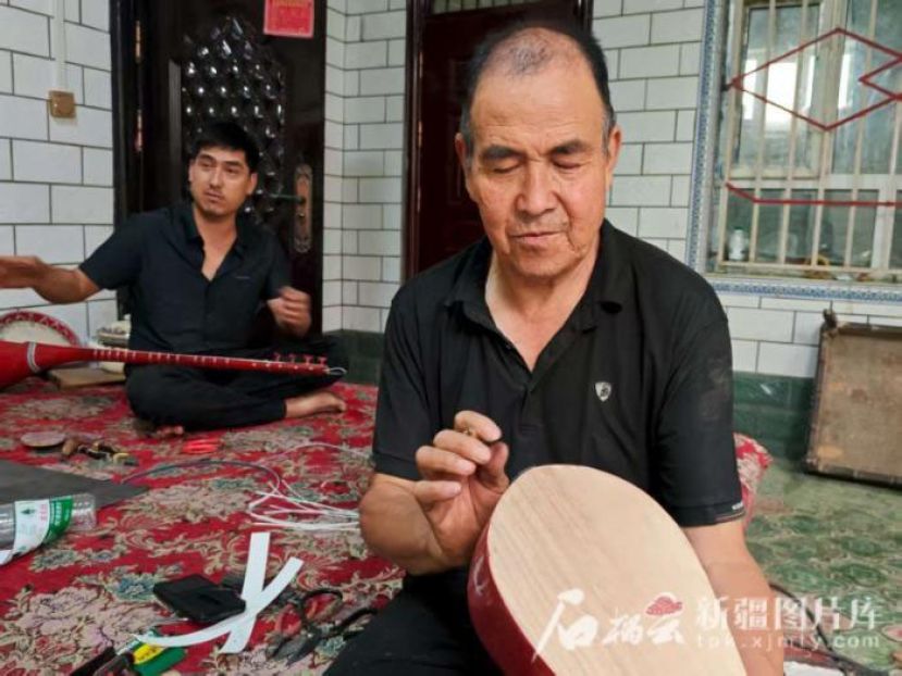 努尔冬&middot;司马义检查乐器。