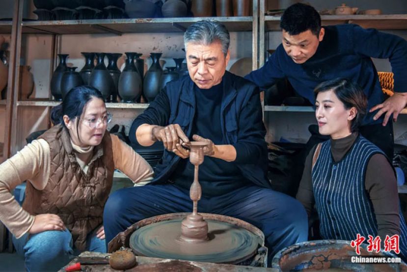 中国黑陶艺术大师邢葆东在拉制蛋壳黑陶高柄杯坯。