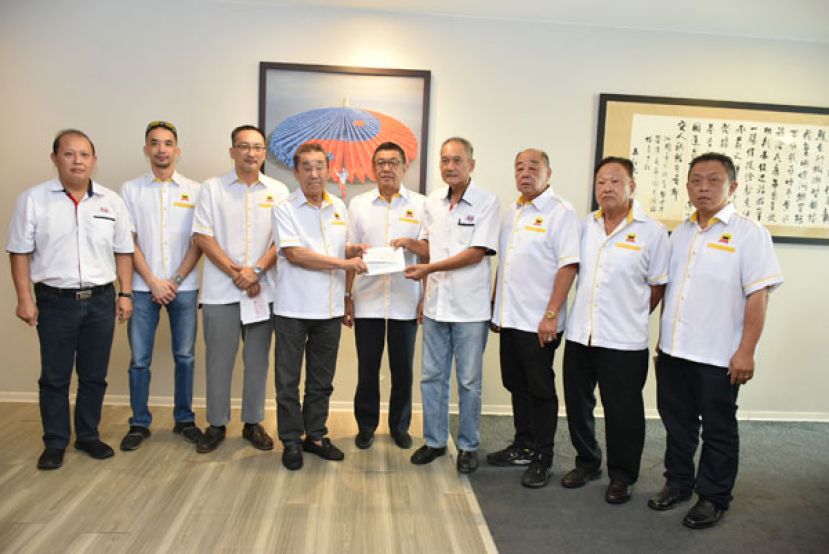 古晋华人信托委员会主席黄良杰（中）见证下，古晋华人信托委员会执行顾问黄张金发（左四）移交  拨款予古晋中中校董会署理主席高伟宁（右四）。右起为古晋华人慈善信托委员会理事甲必丹陈德明、委员  郑瑞福、吴祖姜。左起为古晋中中校董会财政郑雅泰、理事黄维玄与财政郭镕华。