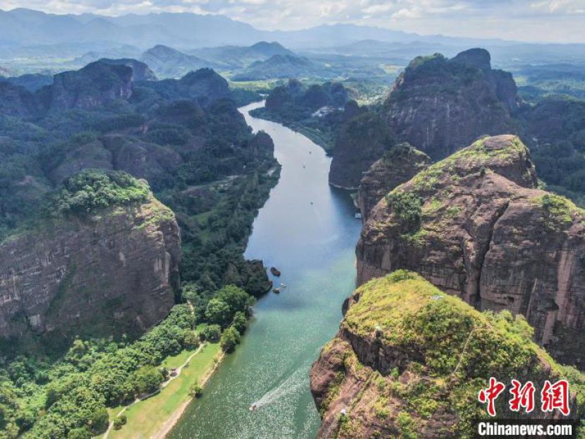 航拍江西龙虎山泸溪河两岸，水清岸绿，一座座丹霞地貌的山峰形状各异，一艘艘竹筏荡漾在碧波之上，风景秀美。