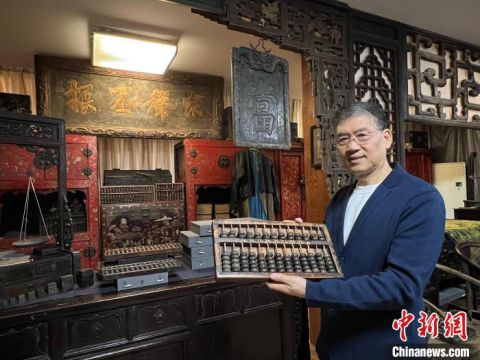 晋商学者、山西财经大学晋商研究院客座教授陈旭向记者介绍自己收藏的算盘。
