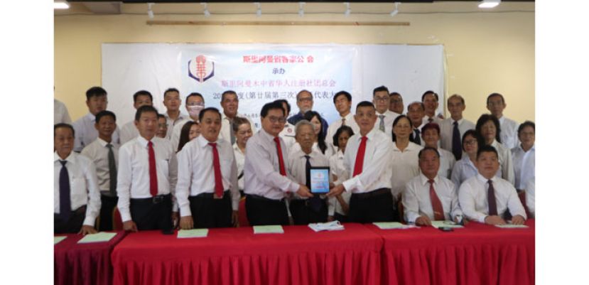 为表感谢，会长吴标生（左）赠送纪念品予主办属会，斯省客家公会。由署理主席李志平接收。