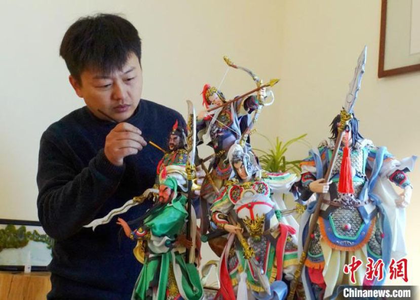周林泽为桂林面塑作品《五虎上将》做收尾工作。