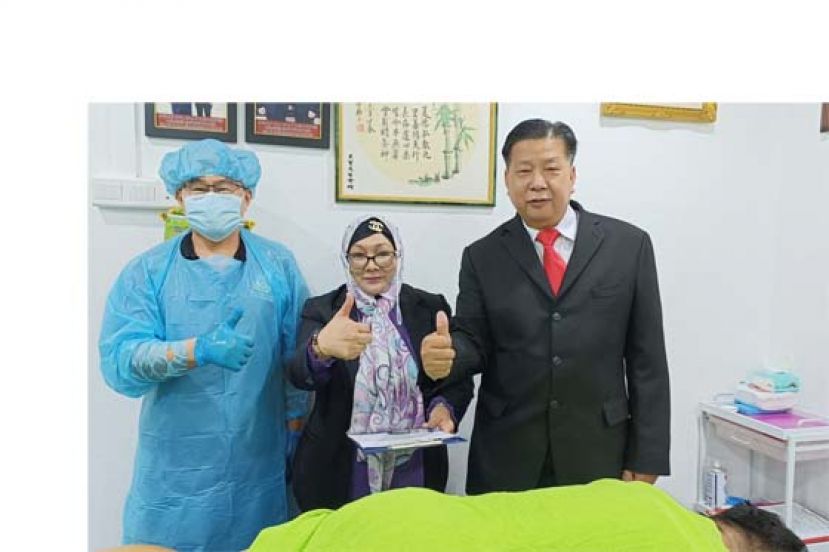 亚洲中医技职学院院长江宗兴（右起）陪同人力资源部技职局考官为一学员在该院推拿理疗技职（SKM）考试中竖起大拇指。